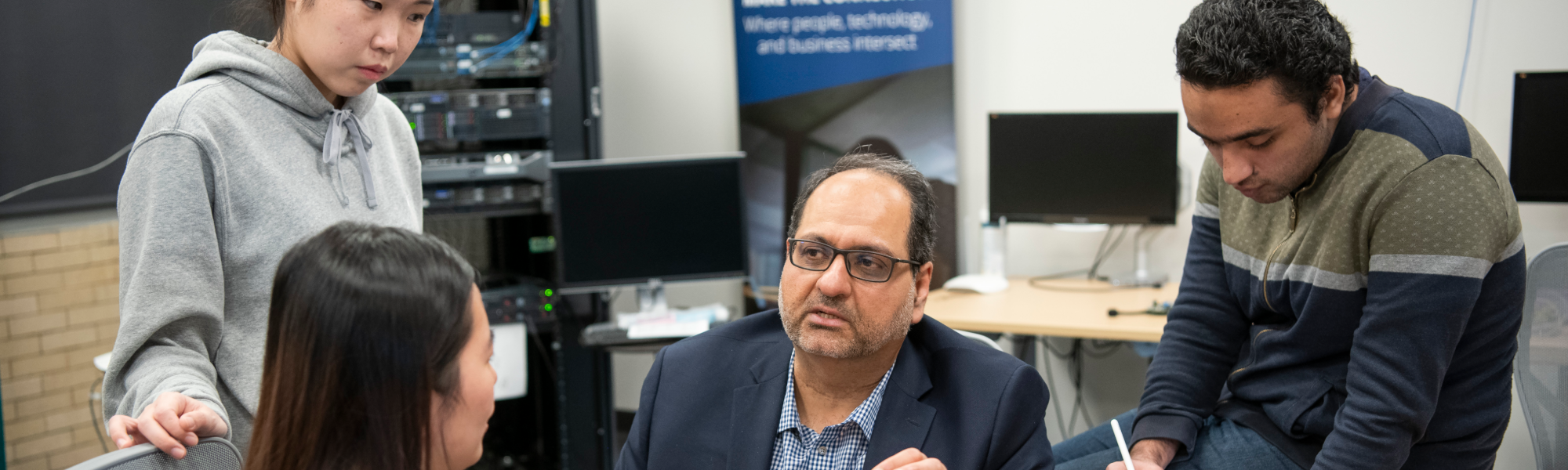 A group of people are in a tech-focused office setting, engaging in discussion.
