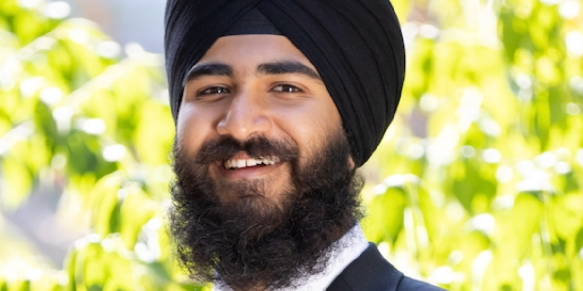 Close-up of Anitvir Singh Taunque wearing a black turban, dark suit jacket, and light-colored collared shirt.