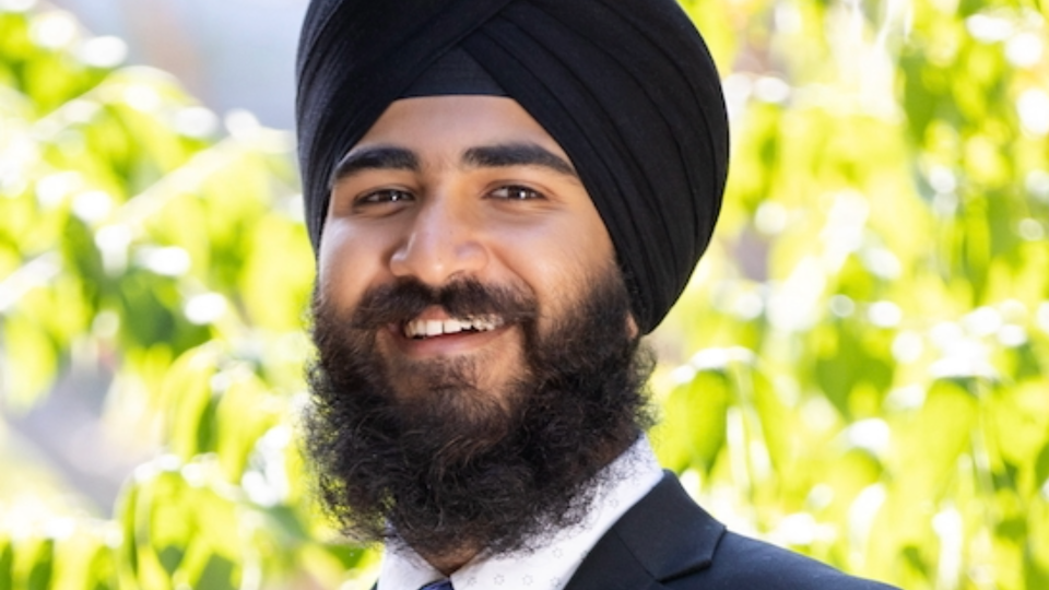 Close-up of Anitvir Singh Taunque wearing a black turban, dark suit jacket, and light-colored collared shirt.